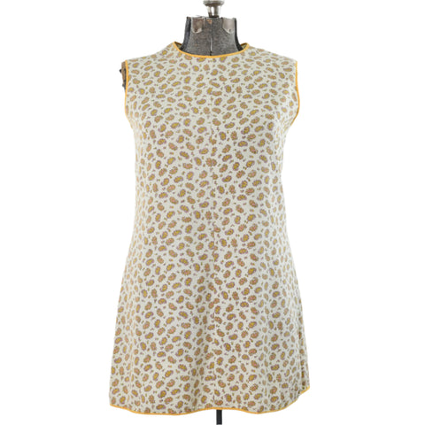 1960s sleeveless mini white dress piped in yellow with paisley pattern shown on dress form against white background
