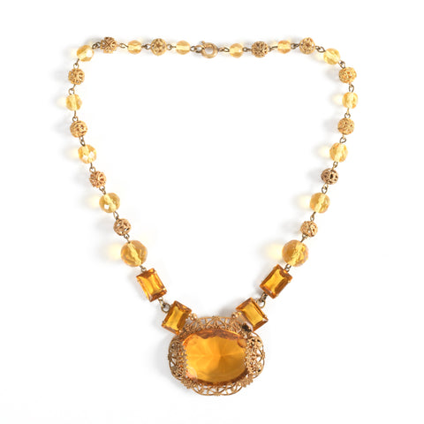 vintage 1930s amber Czech glass brass filigree bead short necklace lying flat on white background