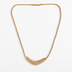 vintage 1970s gold color rope chain 16 inch necklace with V shaped pendant filled with small Swarovski crystals shown lying flat on white background