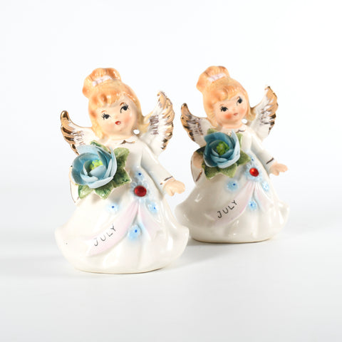 true vintage 1960s lefton July birthday ceramic angels holding blue flowers with ruby rhinestone on dress sash with one angel sitting forward and other behind it back right image all on white background