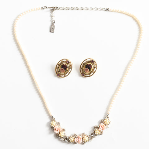 true vintage 1980s single strand pearl necklace with three center panels each with a cluster of faux pearls and center pink porcelain rose with rose printed porcelain in brass colored metal earrings sitting in center of necklace all lying flat on white background