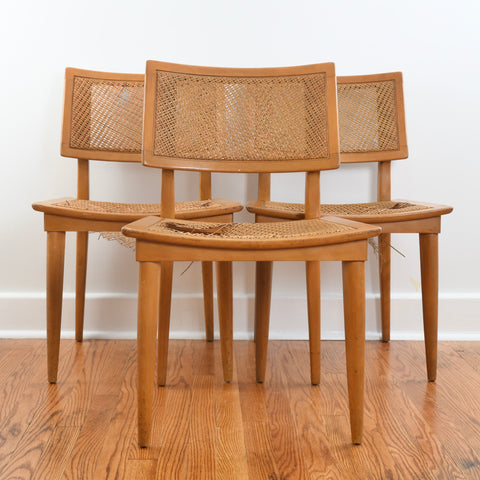 true vintage 1950s modern line caned back and seat 3 wheat colored Heywood Wakefield dining chairs with two in back and one in front center on hardwood floor and white wall
