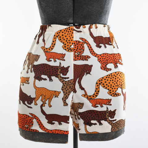 true vintage white background orange, yellow orange, brown and beige with black spots wild cats in various standing and pounce positions shown on dress form on white background