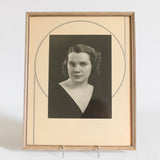 true vintage 1930s cream silver black art deco matted framed glamorous woman headshot portrait wearing a deep V black shirt shown standing on stand with white background