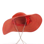 true vintage 1940s burnt orange finely woven raffia straw floppy brim sun hat with orange velvet crown trim that dips under brim with bow to tilt shown on thin silver metal hat stand on white background