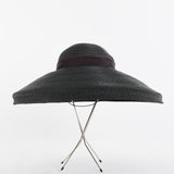 vintage 1940s black raffia new look wide brim sun hat shown on thin silver metal hat stand on white background