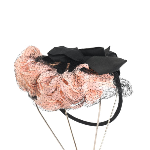 true vintage 1940s pink caged feathers in black netting with black grosgrain ribbons attached to a ring tilt hat shown on thin silver metal wire hat stand on white background