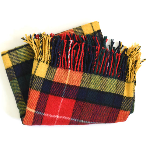 true vintage late 70s wool plaid tartan yellow, red, white, green blue, black woven blanket shown lying flat on white background folded into a square slightly off showing the fringe pointed towards top right 