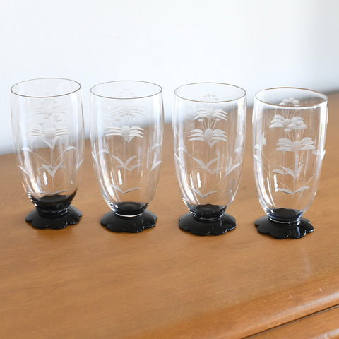 true vintage 1930s weston etched black pond lily foot ice tea glasses set of four lined in row on warm wood with white wall behind it 