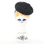 true vintage 1940s black curly Persian lamb round donut tilt hat with black grosgrain ribbon headband shown on ceramic face head form against white back drop