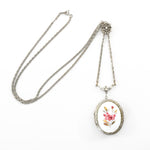 true vintage 1960s Victorian revival silver slide chain milk glass floral painted locket shown draped across white background with locket at bottom right corner