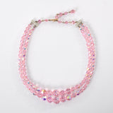 true vintage 1950s pink iridescent beaded aurora borealis necklace with rhinestone ends shown in circle lying on white background