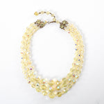 true vintage 1950s yellow iridescent 3 strand aurora borealis crystal beaded necklace shown lying in a circle on white background