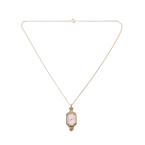 true vintage 1970s ice pink camphor glass with center rhinestone gold tone metal setting pendant on gold tone rope chain lying in inverted triangle on white background