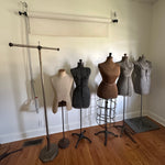 antique and vintage mannequin dress forms shown against white wall with hardwood floor and natural light