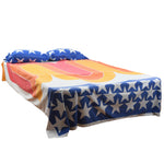 true vintage 1970s funky flat sheet shown on full size bed with white stars an blue print at bottom of flat sheet with large swirls of various shades of orange for main body of sheet with two pillow cases with same blue and white stars pattern shown on white background