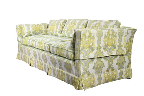 true vintage 1970s green yellow gray white damask floral tuxedo couch shown angled towards left on brown wood laminate floor and white wall