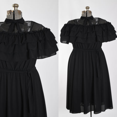 true vintage 1970s polyester black midi dress with sheer illusion neckline with high neck bow and caped tiered bodice ruffles, elastic waist showing details of bodice close up on left side with full dress on dress form right image all on white background