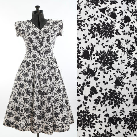 vintage 1950s white cotton black novelty print full skirted short sleeve dress shown on dress form left image and close up of novelty print with trees, a farmer, silhouettes of people courting and riding horses on right image all on white background