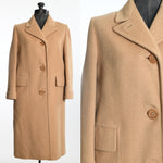 vintage late 1950s tan camel hair box coat with three large center buttons and pick stitching on collar and large flap pockets shown on dress form left image and close up of bodice right image all shown on white background