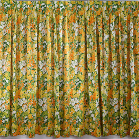 vintage 1960s bold spring floral print of daffodils, tulips, iris in shades of yellow, orange, white and green large panel pinch pleat curtains hanging on white background