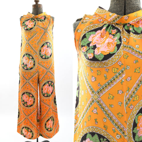 vintage 1960s orange jumpsuit with large pink roses backed by circles of black with diamond geometric patterns with circles and flowers in a sleeveless jumpsuit with wide palazzo pants shown on dress form left image and close up of bodice right image all on white background