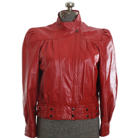 True vintage 1980s red leather puff shoulder jacket with snap button leather straps on bottom hem and asymmetrical zipper shown on dress form on white background