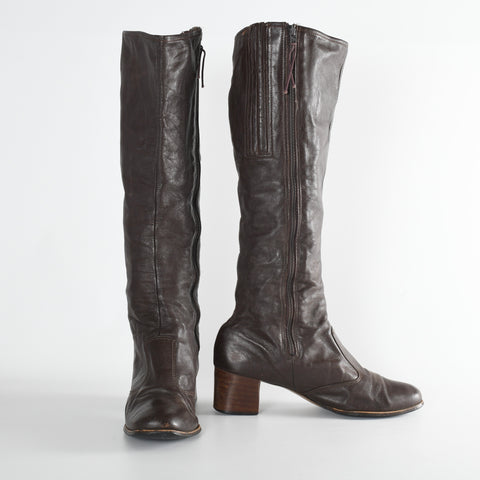 vintage 1970s tall brown leather stacked leather heel zip side boots shown with one pointed forward and other standing at right to the side on a white background