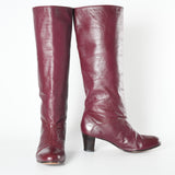 vintage 1970s tall oxblood red leather boots with rounded toe and stacked heel with left image boot facing forward and right image boot turned to side on white background