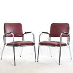 vintage 1940s early 50s red Naugahyde chrome frame black bakelite arm chairs angled toward each other on a white background