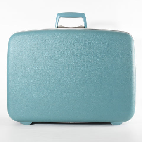 vintage 1950s biscayne blue textured hard sided suitcase with silver trim rubber handle standing up shown on white background