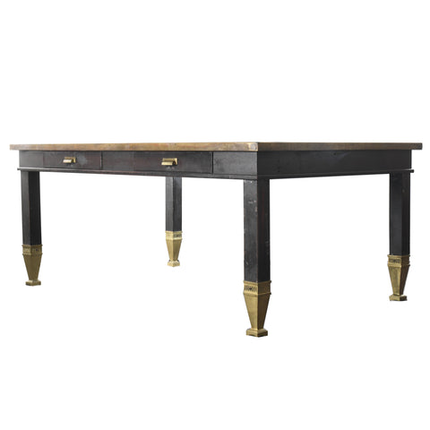 antique 1920s industrial steel table with gold colored feet and dark patina painted steel with 2 drawers and gold colored trim angled to the left shown on white background