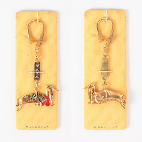 vintage 1960s tourist keychain from Mallorca Spain shown front and back on original packaging, lever latch top with bull and matador  while the other shows back of the keychain
